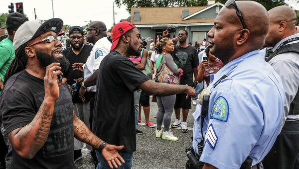 Местные жители и полицейские на улице Сент-Луиса после инцидента, в ходе которого был застрелен афроамериканец