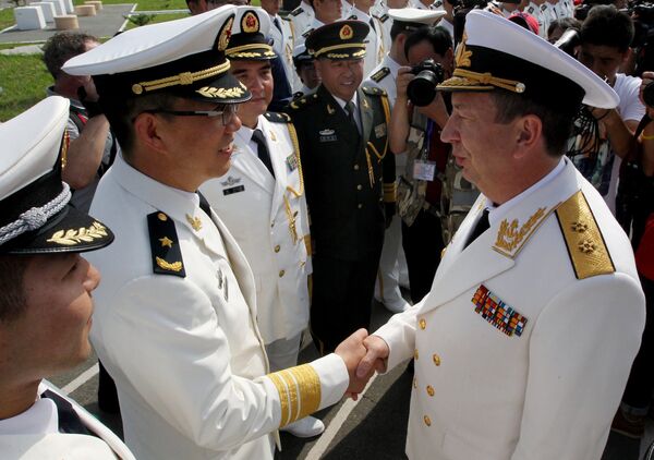 Заместитель главнокомандующего ВМФ РФ вице-адмирал Александр Федотенков (справа) пожимает руку офицеру Военно-морских сил Китая на торжественной встрече кораблей ВМС Китая - участников совместных учений Морское взаимодействие - 2015