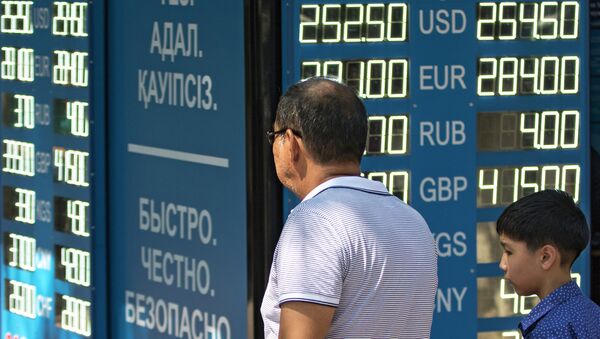 Мужчина с ребенком у информационного табло обменного пункта валюты в Алма-Ате