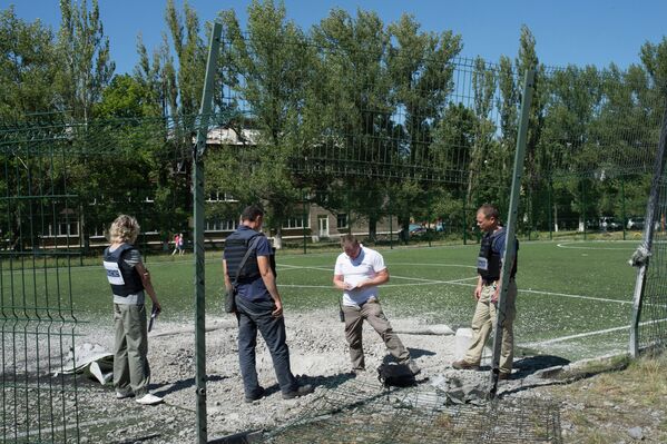Сотрудники миссии ОБСЕ изучают воронку от разорвавшегося снаряда на территории школы № 16
