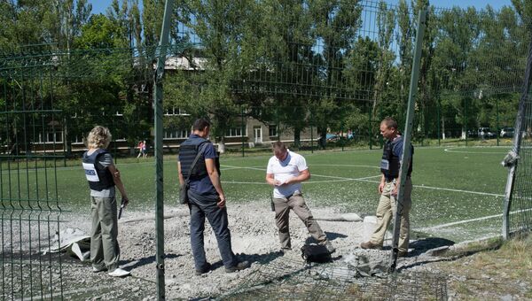 Сотрудники миссии ОБСЕ изучают воронку от разорвавшегося снаряда на территории школы № 16. Архивное фото
