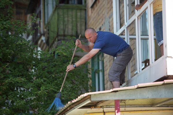 Житель Горловки убирает осколки стекол из выбитых окон многоквартирного жилого дома
