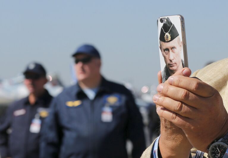 Посетитель на III Международном авиационно-космическом салоне МАКС фотографирует на телефон с изображением Владимира Путина