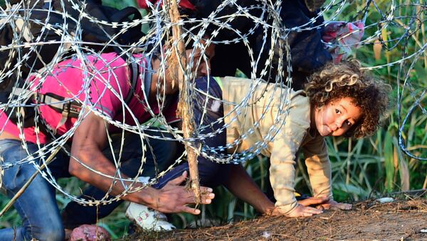 Мигранты проползают под колючей проволокой на Венгерско-Сербской границе