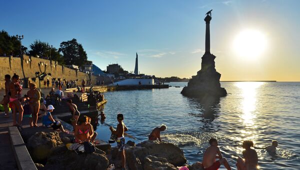 Отдыхающие и местные жители купаются у памятника затопленным кораблям на закате недалеко от Приморского бульвара в Севастополе. Архивное фото