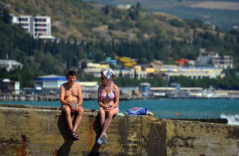 Отдыхающие загорают на волнорезе Профессорского уголка в Алуште