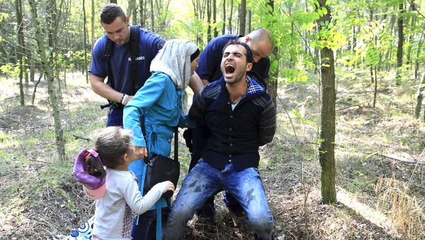 Венгерские полицейские задерживают семью сирийских беженцев после их незаконного пересечения границы с Сербией