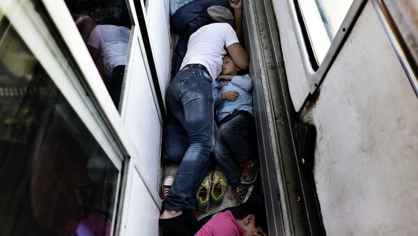 Беженцы из Сирии спят на полу поезда из Македонии в Сербию. 30 августа 2015