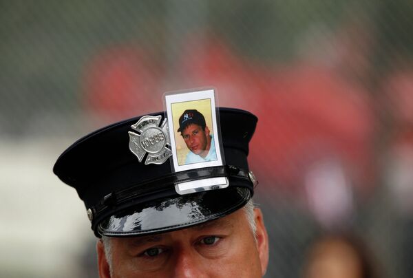 Пожарный с фотографией жертвы теракта 11 сентября 2001 года в Нью-Йорке на церемонии по случаю 10-й годовщины с момента трагедии