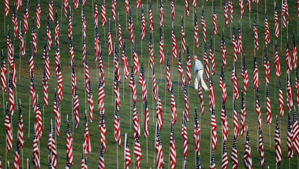 Мужчина идет среди флагов, выставленных по случаю 10-й годовщины с момента теракта 11 сентября 2001 года в Нью-Йорке