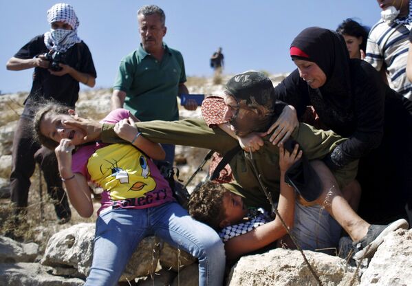 Палестинцы дерутся с израильским солдатом во время акции протеста недалеко от Рамаллы