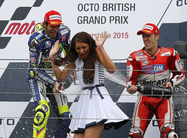 Гонщики Валентино Росси и Андреа Довизиосо обливаются шампанским после Гран-при Великобритании в Сильверстоуне