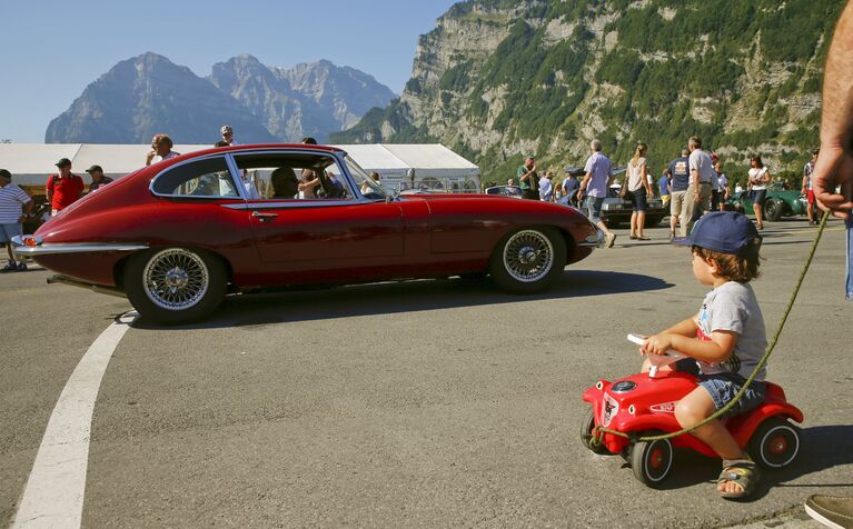 Мальчик смотрит на старинный автомобиль Jaguar E-Type