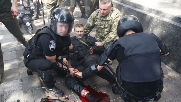 Сотрудники полиции оказывают помощь раненому коллеге после столкновения с активистами возле Верховной Рады Украины в Киеве