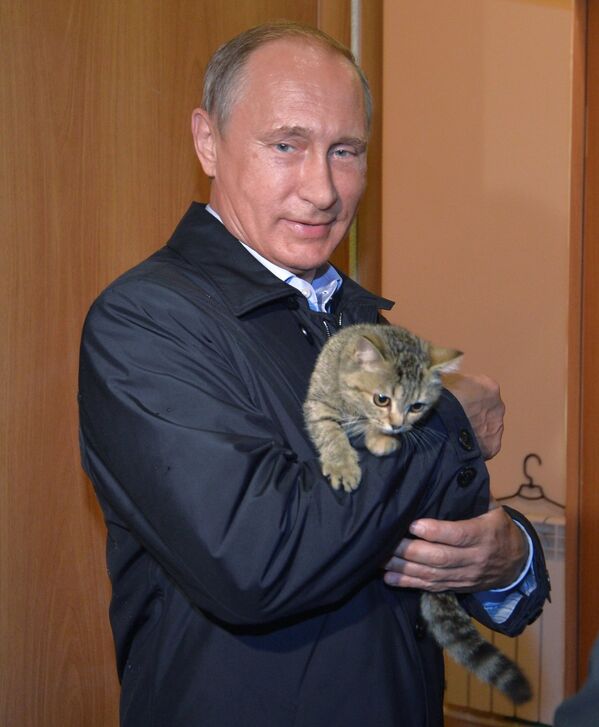 Президент России Владимир Путин держит на руках кошку во время проверки хода строительства жилья для пострадавших от пожаров в селе Краснополье