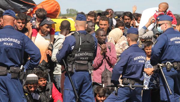 Венгерские полицейские встречают беженцев, заходящих на территорию Евросоюза в Венгрии в районе села Рёске