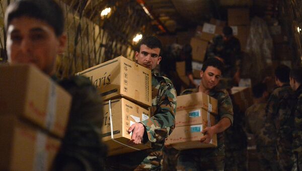 Сирийские военнослужащие разгружают коробки с гуманитарной помощью из России. Архивное фото