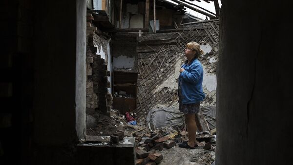 Женщина во одной из комнат своего дома, который был частично разрушен в результате попадания снаряда, в Донецке. Архивное фото