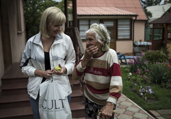 Раиса Барабаш общается с волонтёрами Общества милосердия 77 во дворе своего дома в Донецке