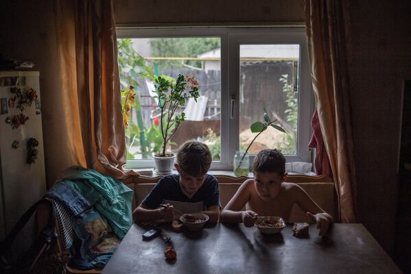 Дети из семьи Ольги Бубновой, чей дом был разрушен в результате попадания снаряда, обедают на кухне своего дома в Донецке