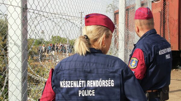 Венгерские полицейские наблюдают за беженцами. Архивное фото