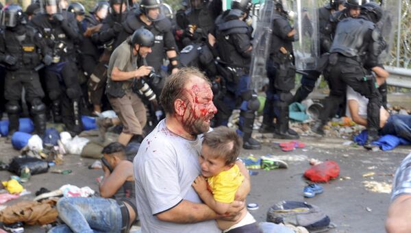 Мужчина с ребенком, пострадавший во время столкновения с полицией на границе Венгрии и Сербии. 16 сентября 2015