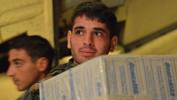 Сирийские военнослужащие разгружают коробки с гуманитарной помощью из России для народа Сирии с борта самолета МЧС РФ. Архивное фото