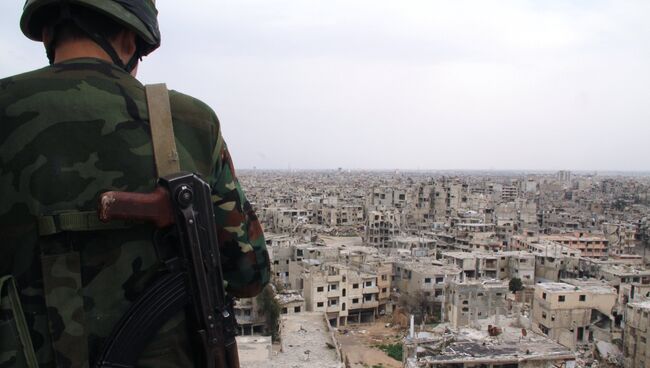 Военнослужащий сирийской армии на крыше одного из зданий, разрушенных в результате боевых действий, в Хомсе. Архивное фото