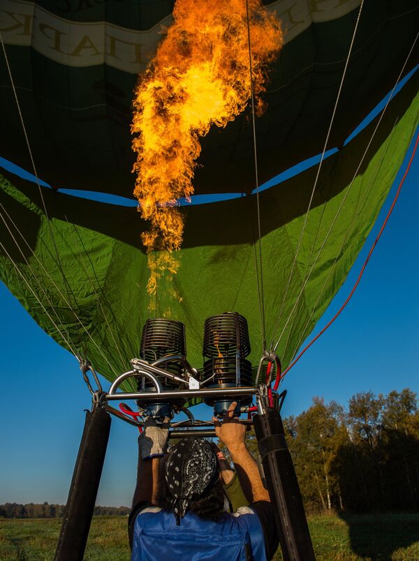 Нагревание воздуха в куполе воздушного шара при помощи горелки во время занятий воздухоплаванием в Московской области