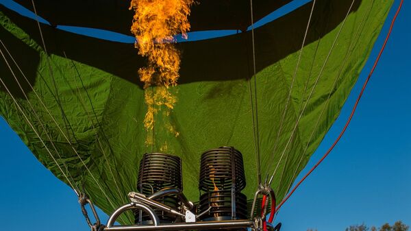 Нагревание воздуха в куполе воздушного шара при помощи горелки во время занятий воздухоплаванием в Московской области