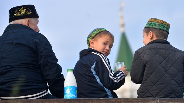 Мужчина с детьми после намаза на берегу озера Кабан у мечети Аль-Марджани в день празднования Курбан-Байрама в Казани