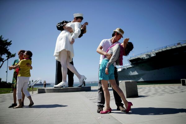 Пара на фоне скульптуры Безоговорочная капитуляция, созданной по мотивам культовой фотографии Поцелуй на Таймс-сквер, в Сан-Диего, США