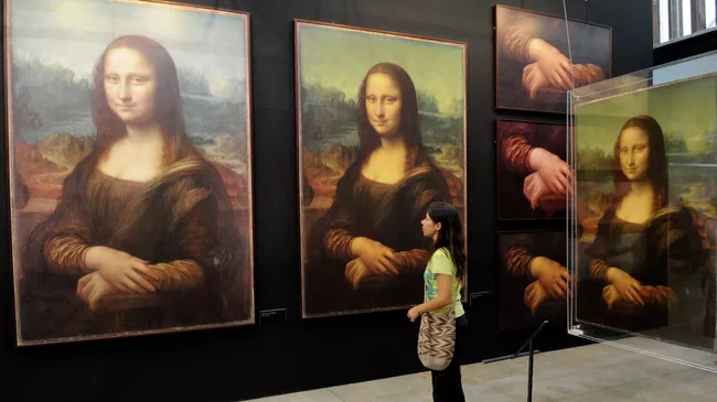 Женщина рассматривает репродукции картины Мона Лиза Леонардо да Винчи. Архивное Фото. Женщина рассматривает репродукции картины Мона Лиза Леонардо да Винчи. Архивное Фото.