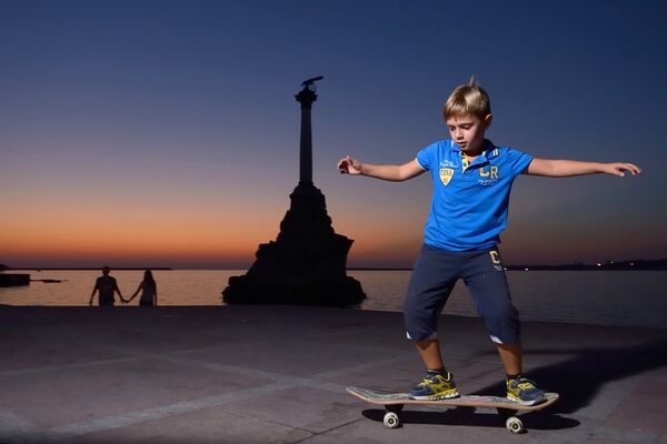 Мальчик катается на скейтборде на набережной в Севастополе