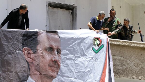Бойцы Национальных сил обороны Сирии вешают портрет Башара Асада в городе Маалула