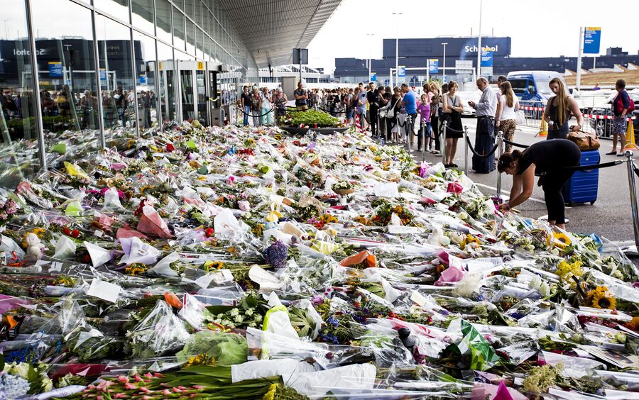 Люди возлагают цветы возле входа в аэропорт Схипхол, Нидерланды