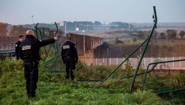 Полицейские у поврежденной ограды туннеля под Ла-Маншем в Кале. Архивное фото