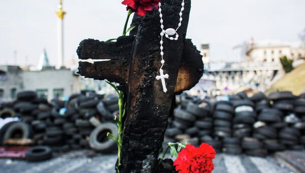 Обгоревшая доска, православный крест и цветы на баррикадах на Институтской улице в Киеве. Архивное фото
