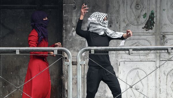 Молодая женщина из Палестины бросает камни в сторону израильских сил безопасности во время столкновений. 7 октября 2015. Архивное фото