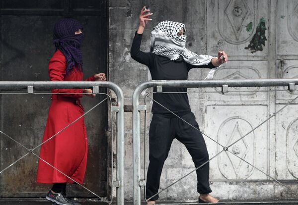 Молодая женщина из Палестины бросает камни в сторону израильских сил безопасности во время столкновений