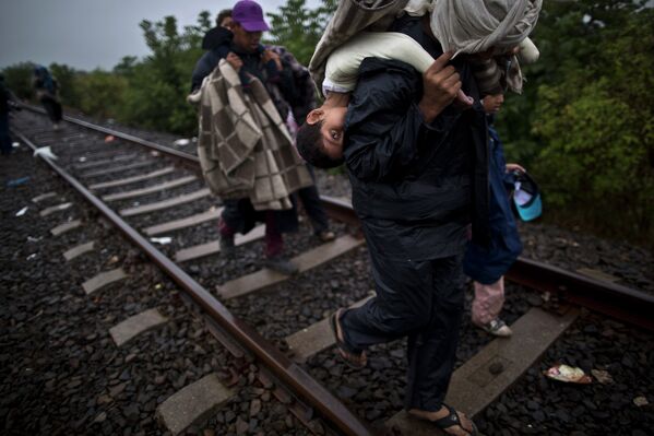 Мигранты из Сирии идут по железнодорожным путям после пересечения границы между Сербией и Венгрией