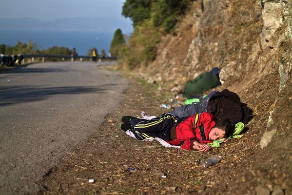 Сирийский мальчик с матерью спят на дороге после прибытия на остров Лесбос