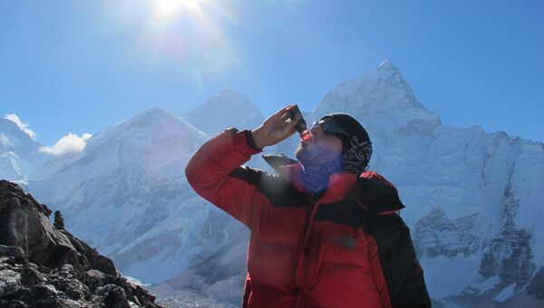 Участник эксперимента пьет свекольный сок во время похода в горы в Непале