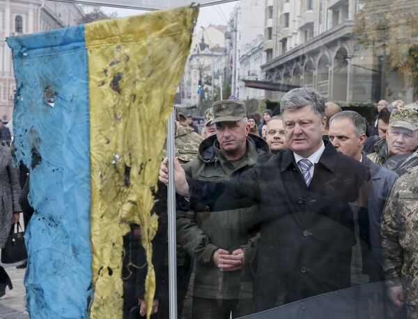 Петр Порошенко смотрит на флаг страны, привезенный с мест конфликта на востоке Украины