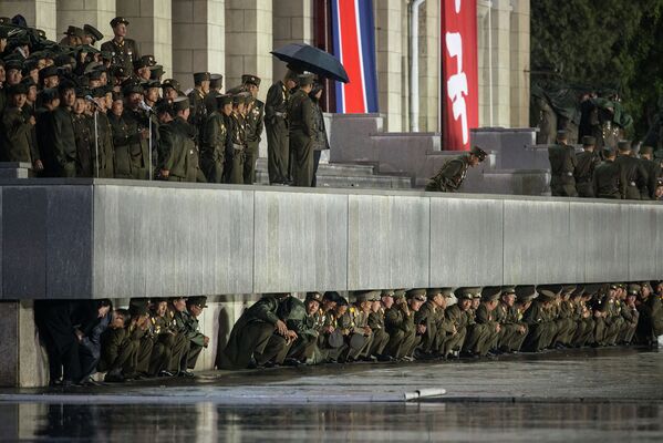 Северокорейские солдаты укрываются от дождя после военного парада в Пхеньяне. Октябрь 2015