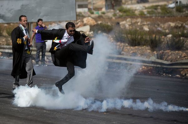 Адвокат пинает канистру со слезоточивым газом обратно в сторону израильских солдат в ходе в Иерусалиме