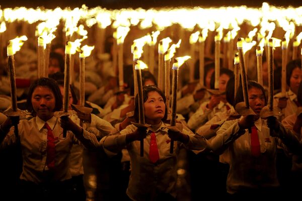 Девочки держат факелы во время празднования 70-й годовщины основания Трудовой партии Кореи, в Пхеньяне