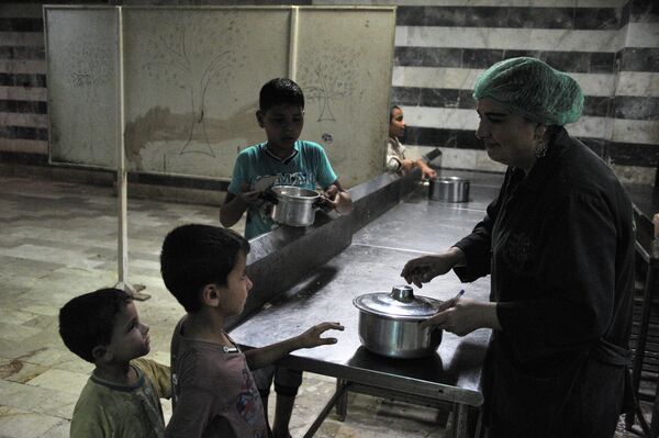 Раздача еды в лагере сирийских беженцев в спортивном комплексе имени Хафеза Асада, Латакия, Сирия