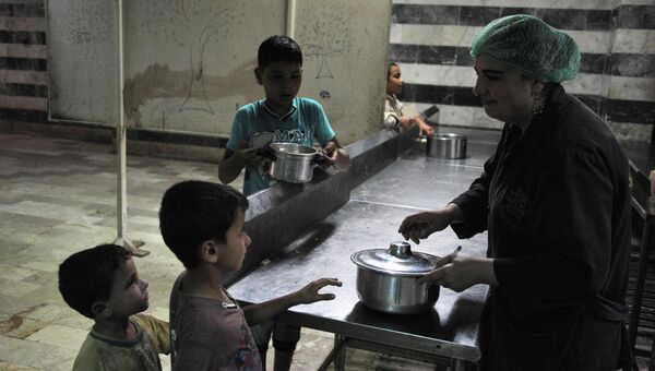 Раздача еды в лагере сирийских беженцев в спортивном комплексе имени Хафеза Асада, Латакия, Сирия. Архивное фото