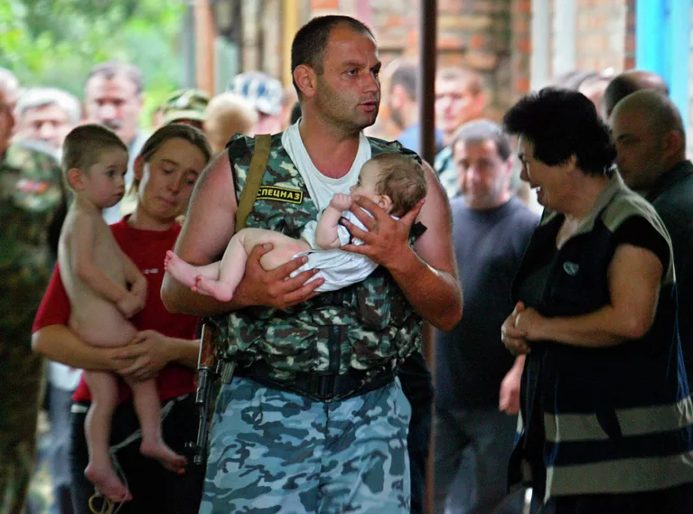Боец спецназа несет спасенного ребенка во время штурма захваченной боевиками школы в Беслане. 2004 год Боец спецназа несет спасенного ребенка во время штурма захваченной боевиками школы в Беслане. 2004 год